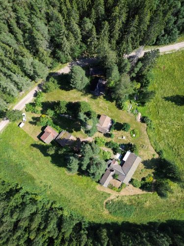 Top-down drone view of the Noord Darkness Retreat cabins and garden surrounded by dense green forest.