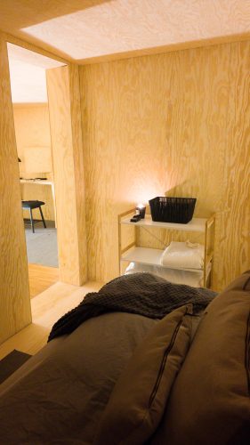 Low bed positioned beside a full-length wall mirror in the wood-lined retreat room.