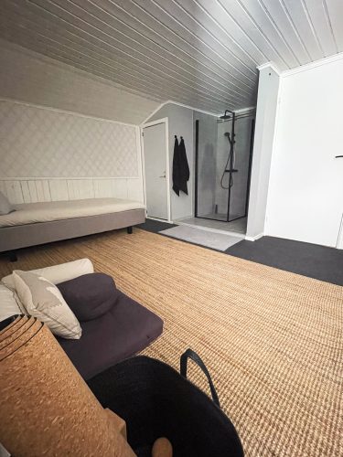 Spacious retreat room with a low bed, woven rug and open entry area.