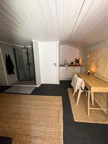 Open cabin doorway beside a simple writing desk and chair.