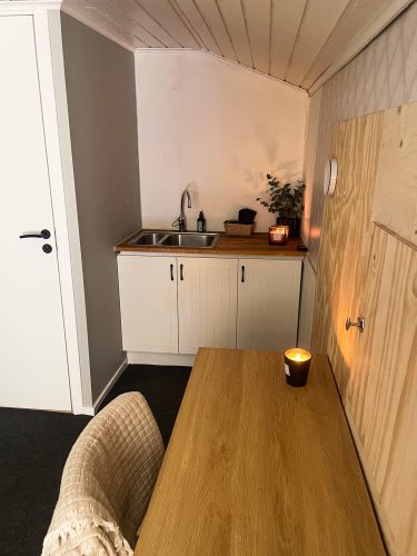 Small kitchenette and open doorway in the warm wood-lined cabin.