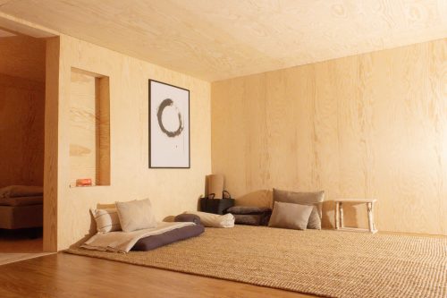 Low beige bed with cushions and framed wall art in the retreat cabin.