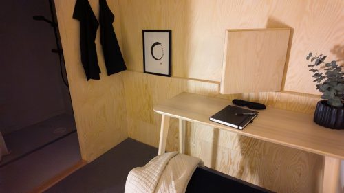 Low bench beside a compact writing desk in the warm wood-lined retreat room.